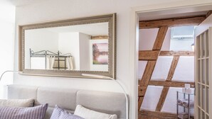 Una habitación con un espejo grande, un sofá con cojines y vistas a una escalera de madera que da a un balcón.