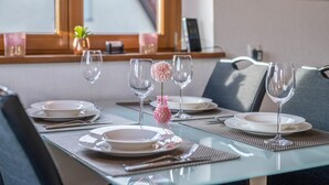 Una mesa con vajilla, vasos y un centro de mesa con una flor rosa.