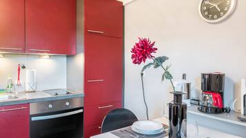 Une cuisine moderne avec des meubles rouges, une machine à café et une horloge au mur.
