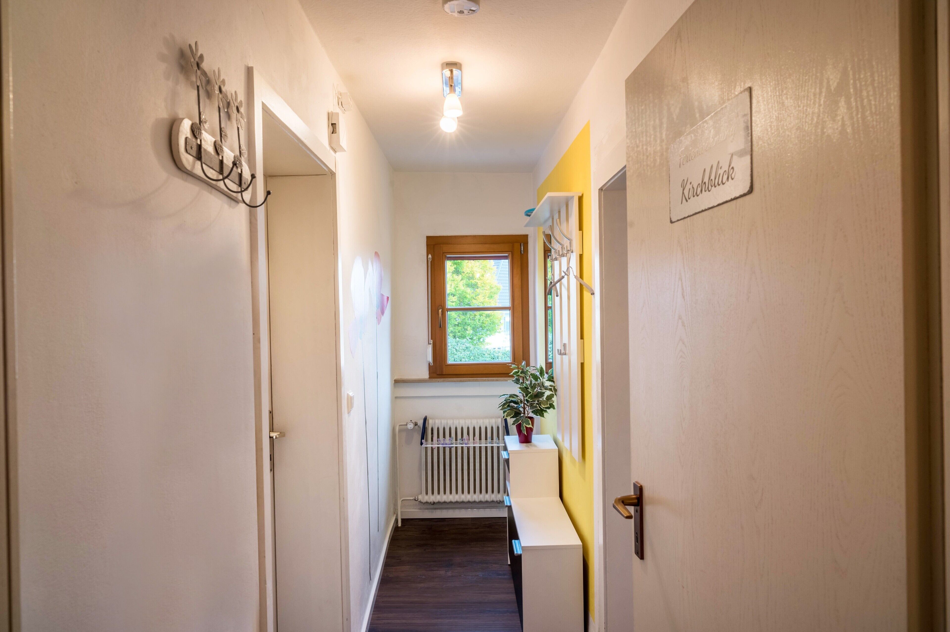 Un couloir avec un radiateur, une fenêtre et une porte.