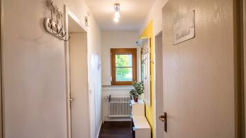 Un couloir avec un radiateur, une fenêtre et une porte.