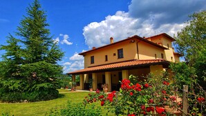 A two-story house with a tiled roof, surrounded by a well-maintained garden with various plants and flowers. - Villa with Pool - 4 rooms with independent bathroom (Rignano sull'Arno)