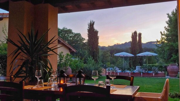 An outdoor dining area with tables and chairs, surrounded by greenery and a view of trees and hills. - Villa with Pool - 4 rooms with independent bathroom (Rignano sull'Arno)