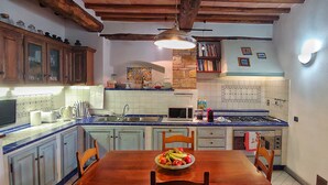 A kitchen with wooden cabinets, a tiled backsplash, a dining table with chairs, and a fruit bowl. - Villa with Pool - 4 rooms with independent bathroom (Rignano sull'Arno)