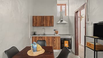 Una cocina compacta con armarios de madera, un lavamanos de acero inoxidable y un horno empotrado.