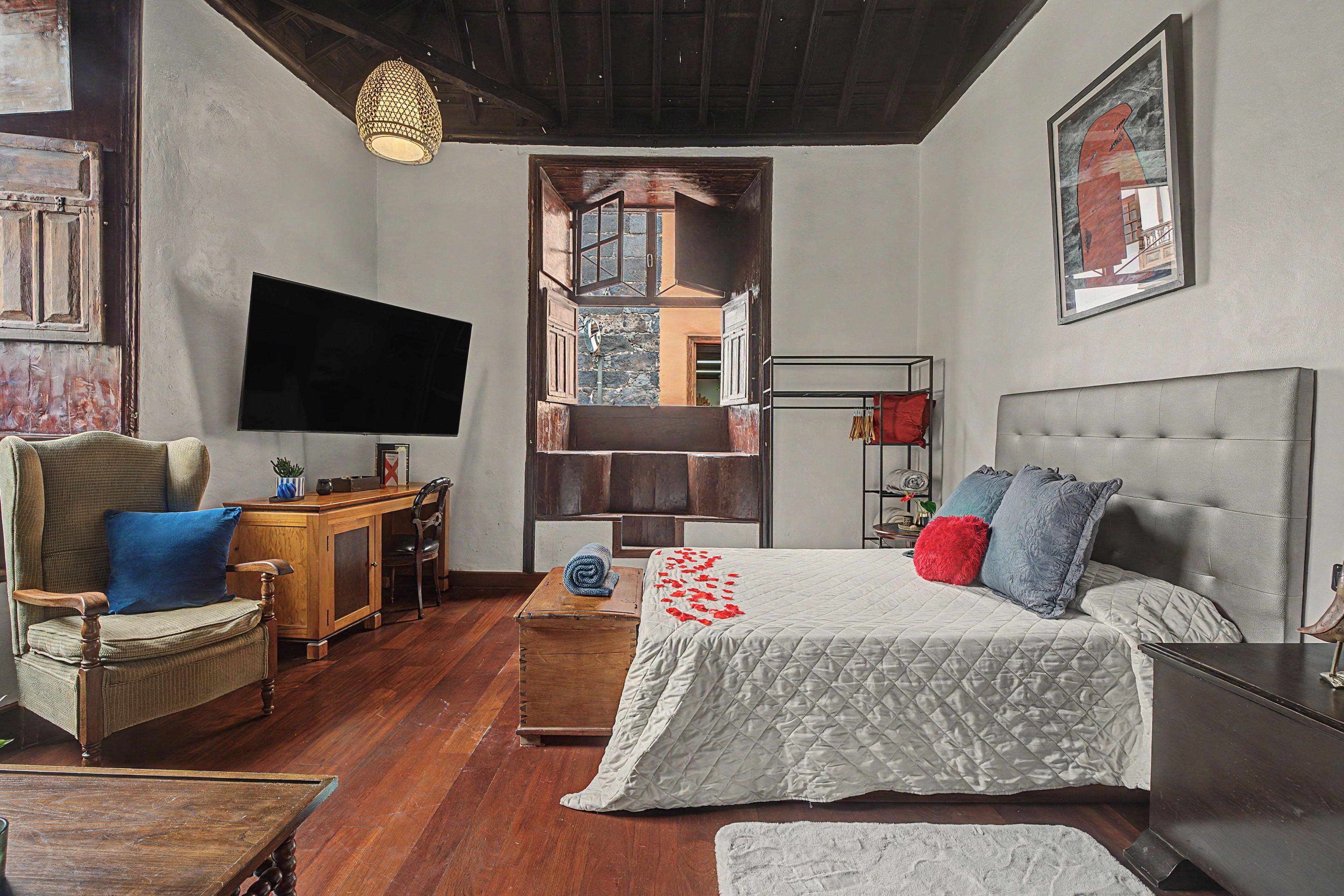 Un dormitorio con cama, escritorio, silla, televisor y armario.