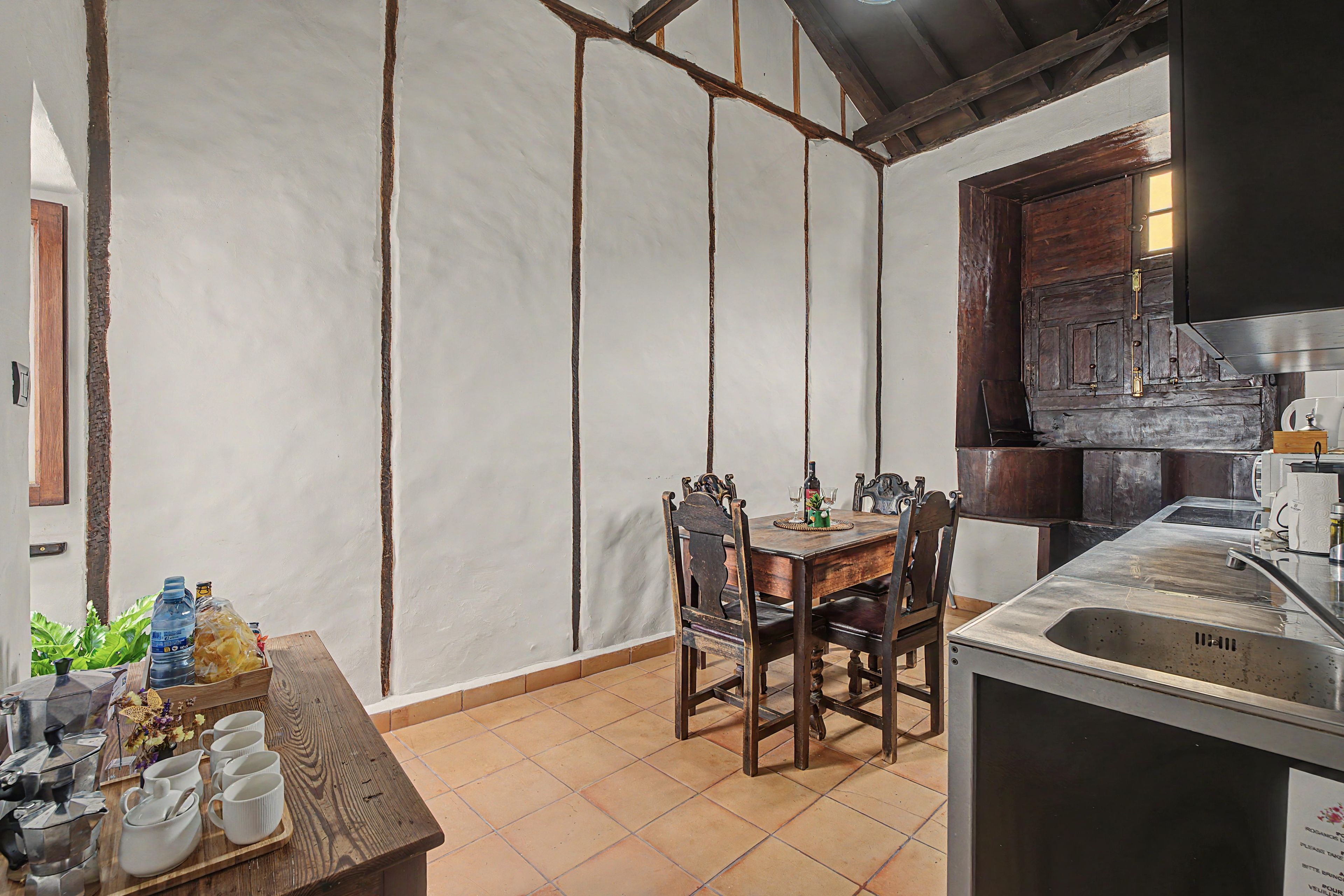 A kitchen with a dining table, chairs, a coffee machine, and a sink.