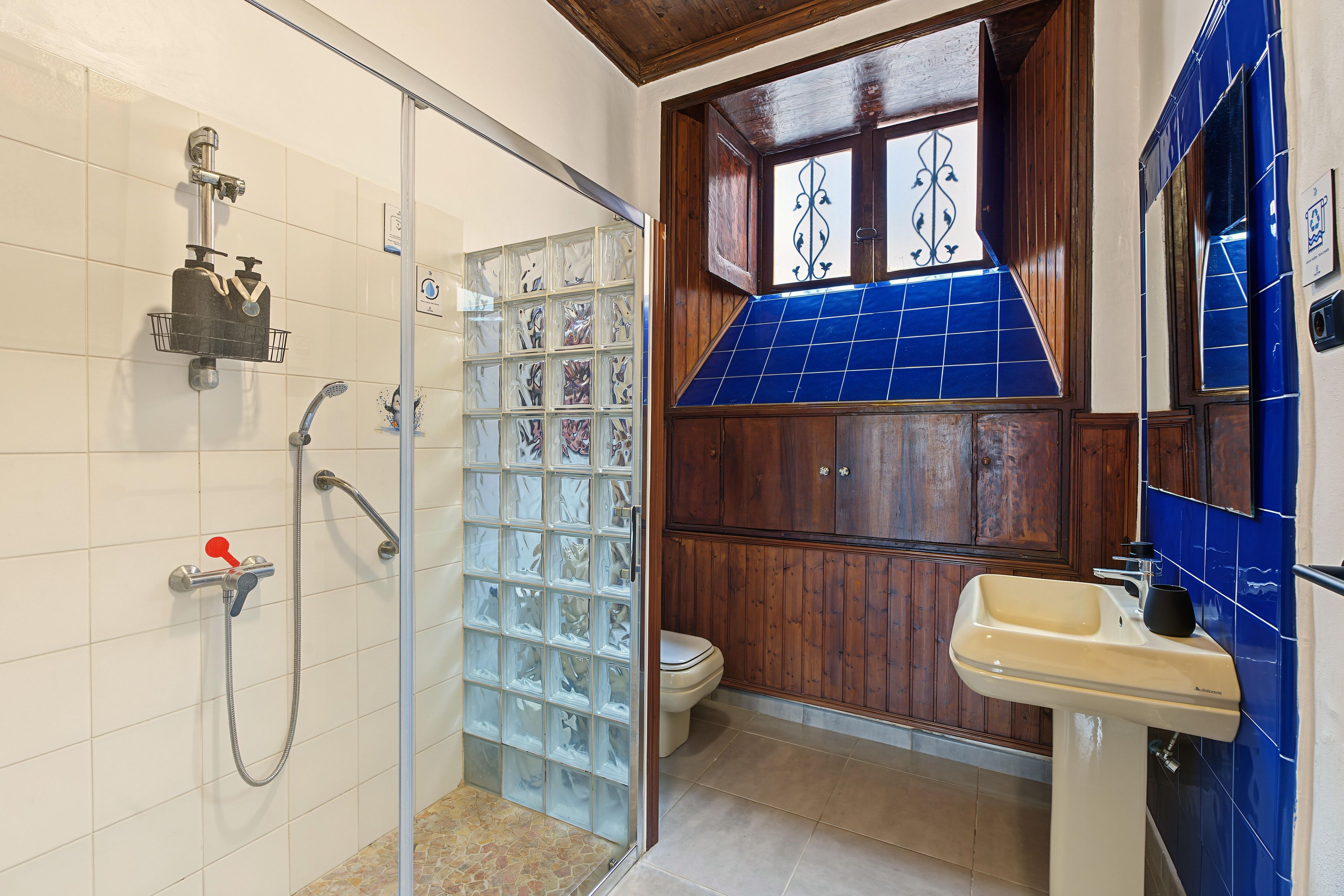 Un baño con cabina de ducha de vidrio, inodoro y lavamanos.