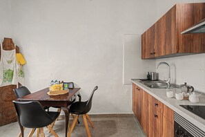 Eine kleine Küche mit Holzausstattung, einer Spüle und einem Essbereich mit zwei Stühlen.