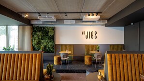 Een modern interieur met zithoeken, een groene wand en een bord met de tekst 'MR JIGS'.