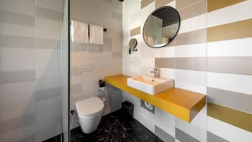 A modern bathroom with a white toilet, a sink with a yellow countertop, and a mirror.
