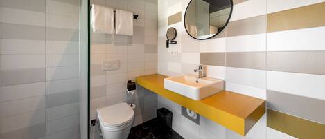 Un baño moderno con inodoro blanco, lavamanos con encimera amarilla y espejo.