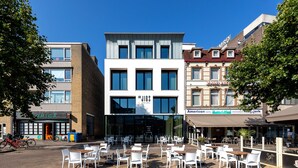 Een modern gebouw met een etalage met de tekst 'JIGS' en een restaurant genaamd 'American Hotel'.