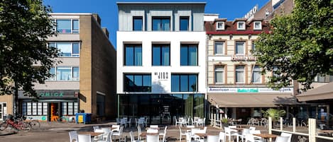 A modern building with a storefront labeled "JIGS" and a restaurant named "American Hotel."