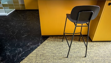 Uma cozinha com bancada amarela, uma cadeira preta e um tapete com padrão preto e amarelo.