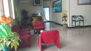 A lobby with red seating, a TV, and a plant. - Hotel Parewisata (Parepare)