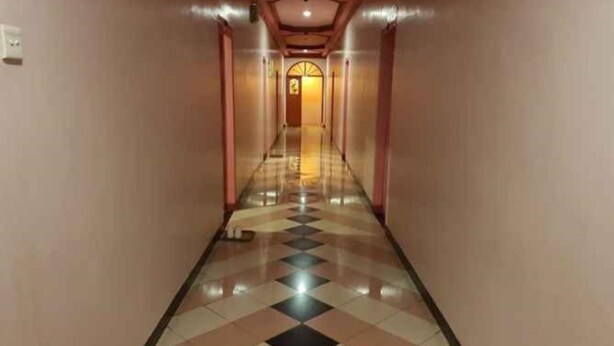 A hotel hallway with a checkered floor pattern, a central light source, and a door at the end. - Hotel Parewisata (Parepare)