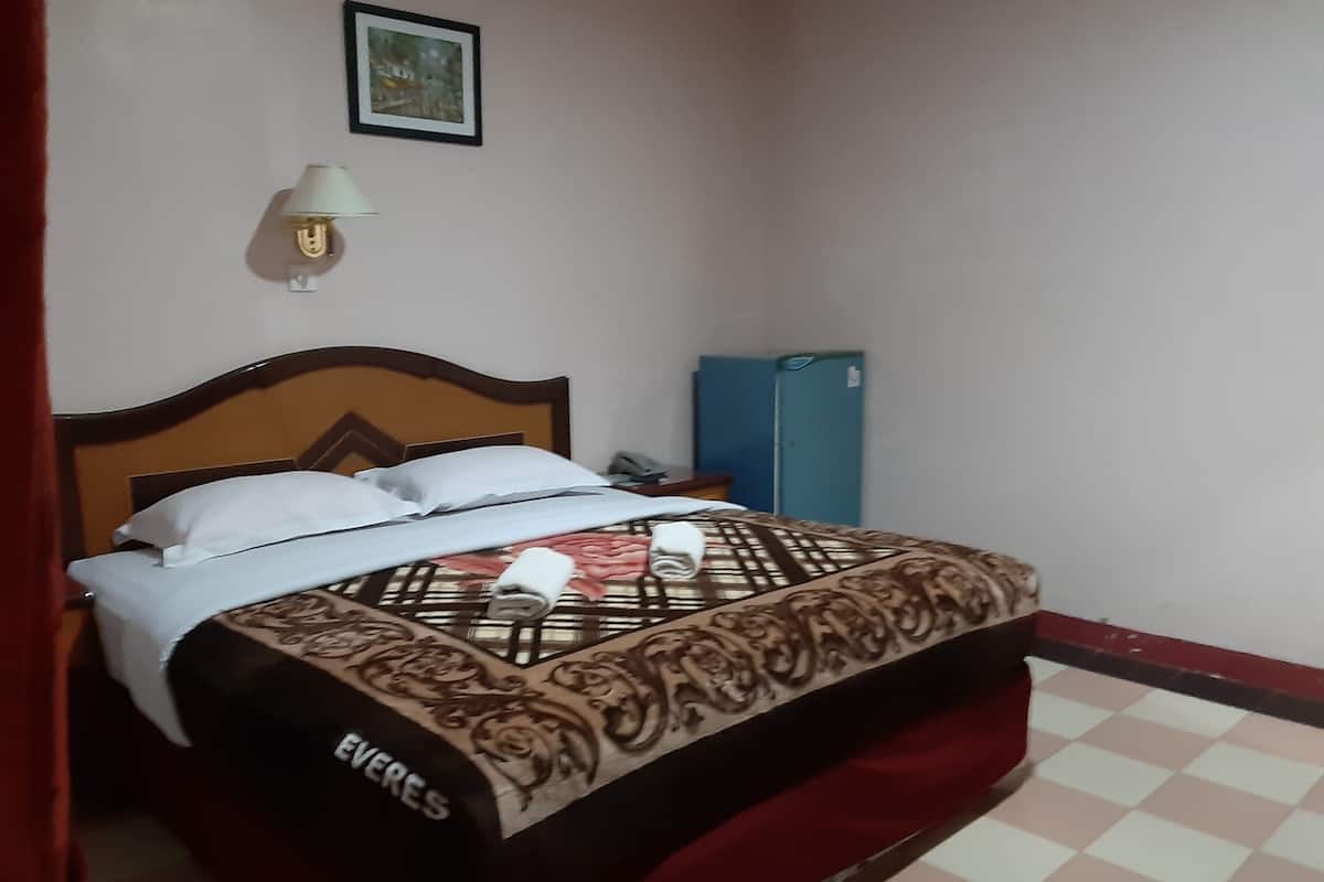 A neatly made bed with a patterned bedspread, a bedside lamp, and a framed picture on the wall.