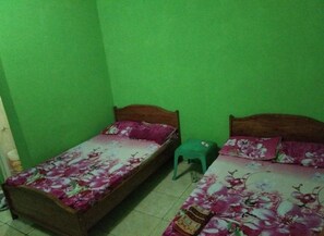 A small, green-walled room with two single beds, each with floral bedding. - Pondok Sundawa (Pangandaran)
