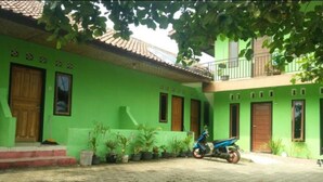 A green building with a tiled roof, a scooter parked in front, and potted plants around. - Pondok Sundawa (Pangandaran)