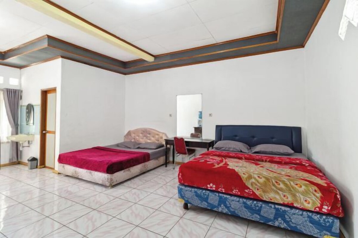 A room with two beds, a desk, and a mirror.