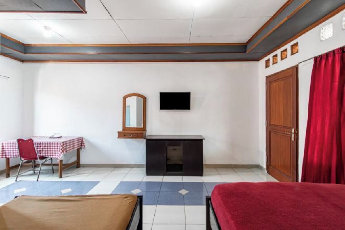 Quarto com cama, escrivaninha, cadeira, televisão e guarda-roupa.