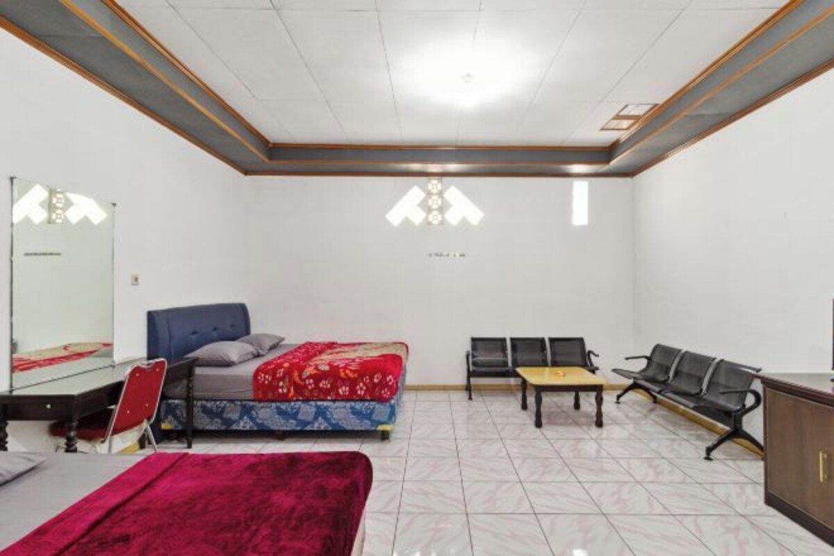 Quarto de hotel com cama, escrivaninha, cadeira, mesa e sofá.