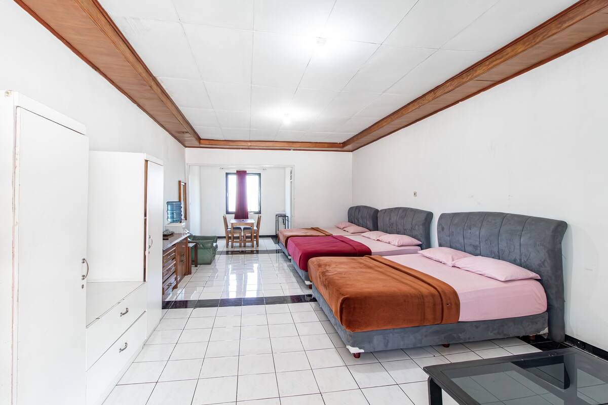 Een kamer met drie bedden, een bureau en een stoel.