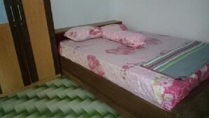 Una habitación pequeña con una cama, un tapete verde y un armario de madera.