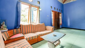 Una habitación con pared azul, un sofá a rayas, una mesita y una puerta que da al exterior.