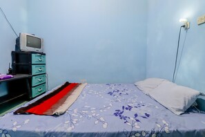 A bedroom with a bed, a dresser, a television, and a wall socket. - Ringin Guesthouse (Kalirejo)