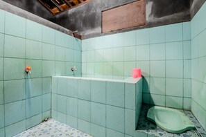 A small, tiled bathroom with a green toilet, a sink, and a shower area. - Ringin Guesthouse (Kalirejo)