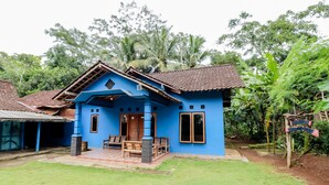 Una casa azul con techo de tejas, un porche con mobiliario de madera y un letrero que dice "Lindin House".