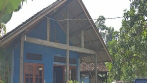 A two-story building with a blue exterior, a covered porch, and a visible garage. - Penginapan Tasya (Kalirejo)