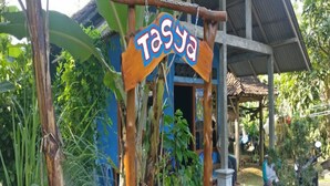 A rustic building with a sign reading "Tasya" and a covered porch area. - Penginapan Tasya (Kalirejo)