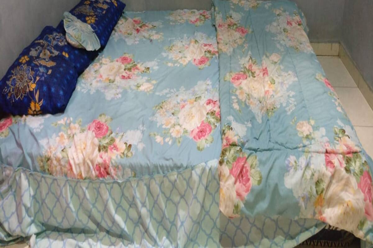 A bed with floral bedding and a blue pillow.