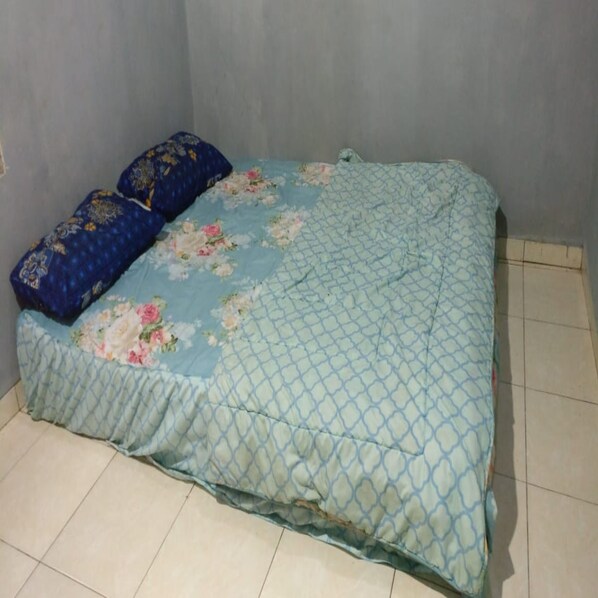 Una cama con una colcha estampada con motivos florales y dos almohadas, una con diseño azul y dorado.