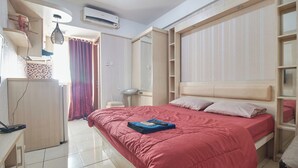 A bedroom with a bed, a desk, a chair, and a wardrobe. - Apartment Green Lake View Ciputat by Celebrity Room (South Tangerang)