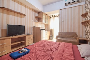 Cozy retreat with a single bed, TV, desk, and wardrobe.