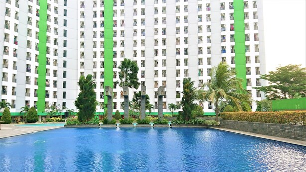 A swimming pool with a view of a tall residential building with balconies. - Apartment Green Lake View Ciputat by Celebrity Room (South Tangerang)