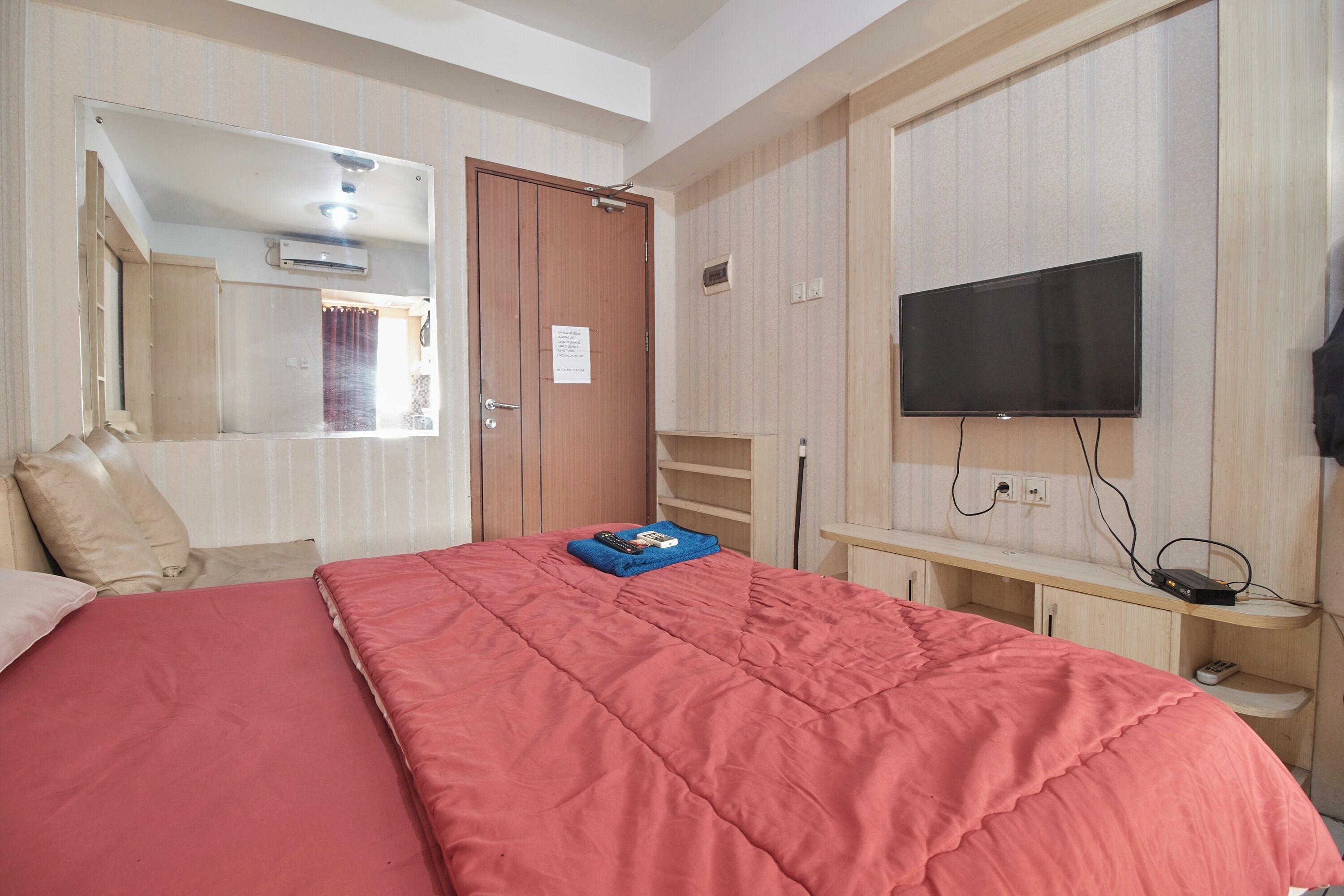 A bedroom with a large bed, a television mounted on the wall, and a wardrobe.