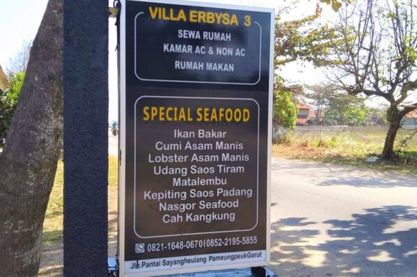 A signboard for Villa Erbysa 3 listing amenities and special seafood dishes.