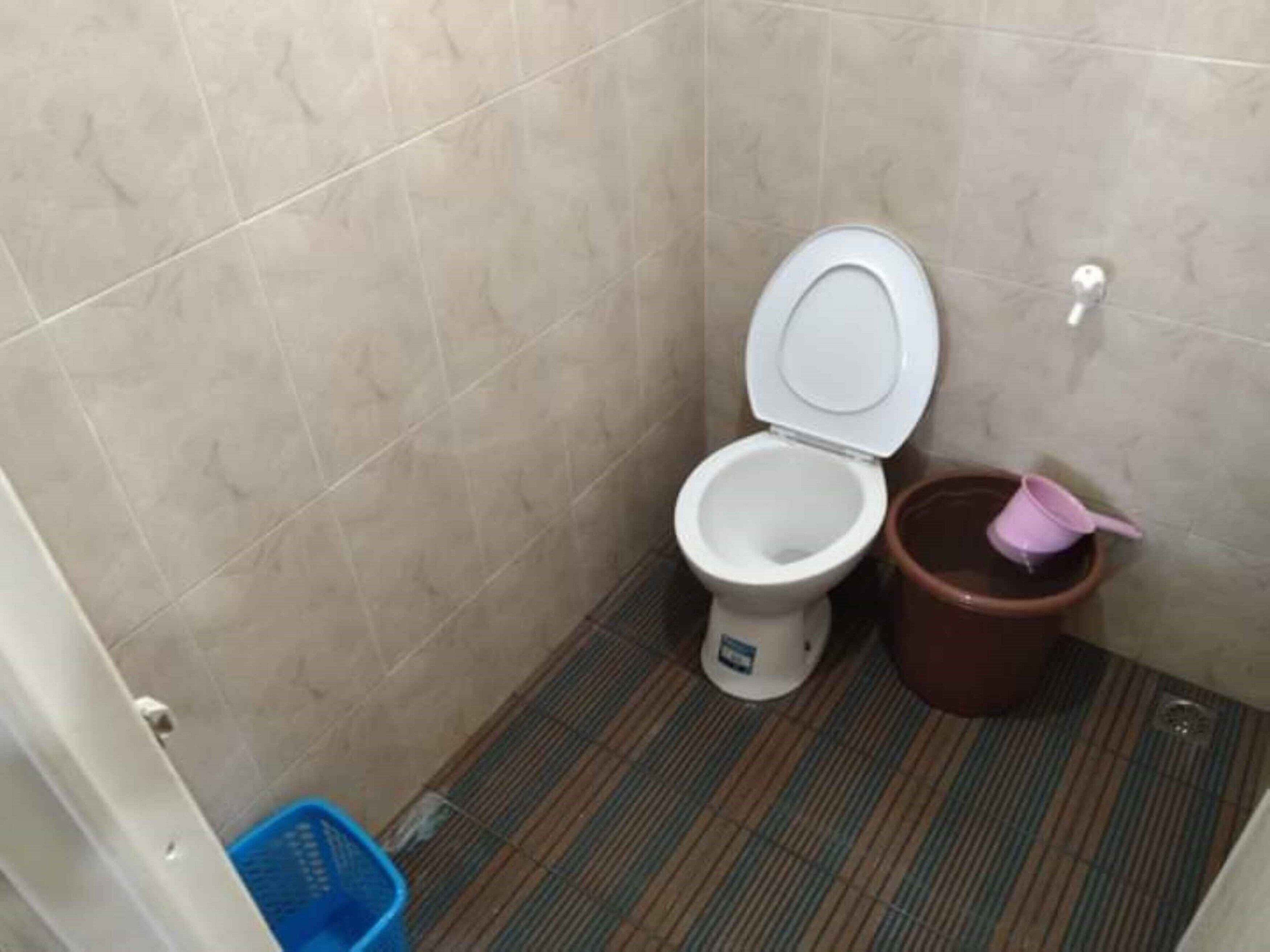 Ein kleines Badezimmer mit Toilette, einem Mülleimer und einem blauen Wäschekorb.
