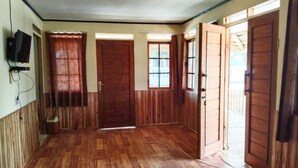 Un couloir doté d’un plancher en bois, d’un téléviseur fixé au mur et d’une porte donnant sur une autre pièce.