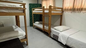 Ein Schlafsaalzimmer mit Etagenbetten, einem kleinen Tisch und einer Klimaanlage.