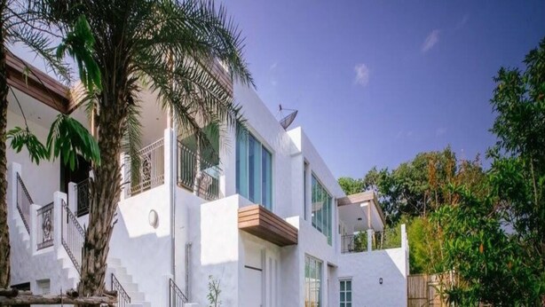A modern house with a wooden deck, a small pool, and a staircase leading to a balcony. - Monkey House (Hang Dong)