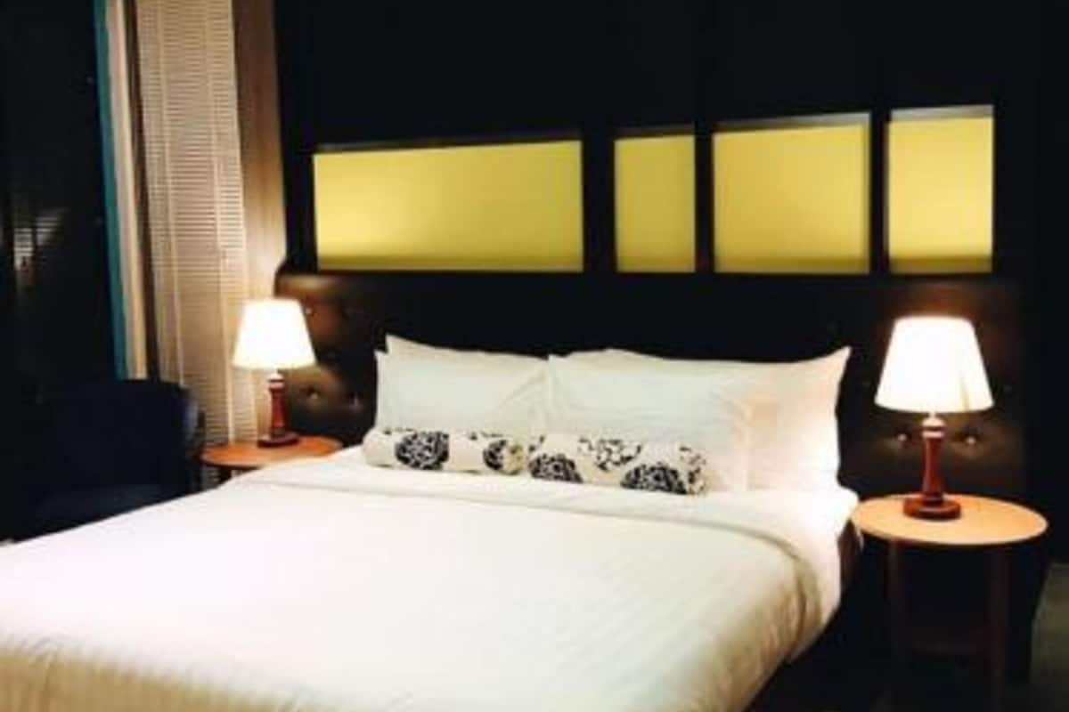 A hotel room with a large bed, two bedside lamps, and a patterned rug.