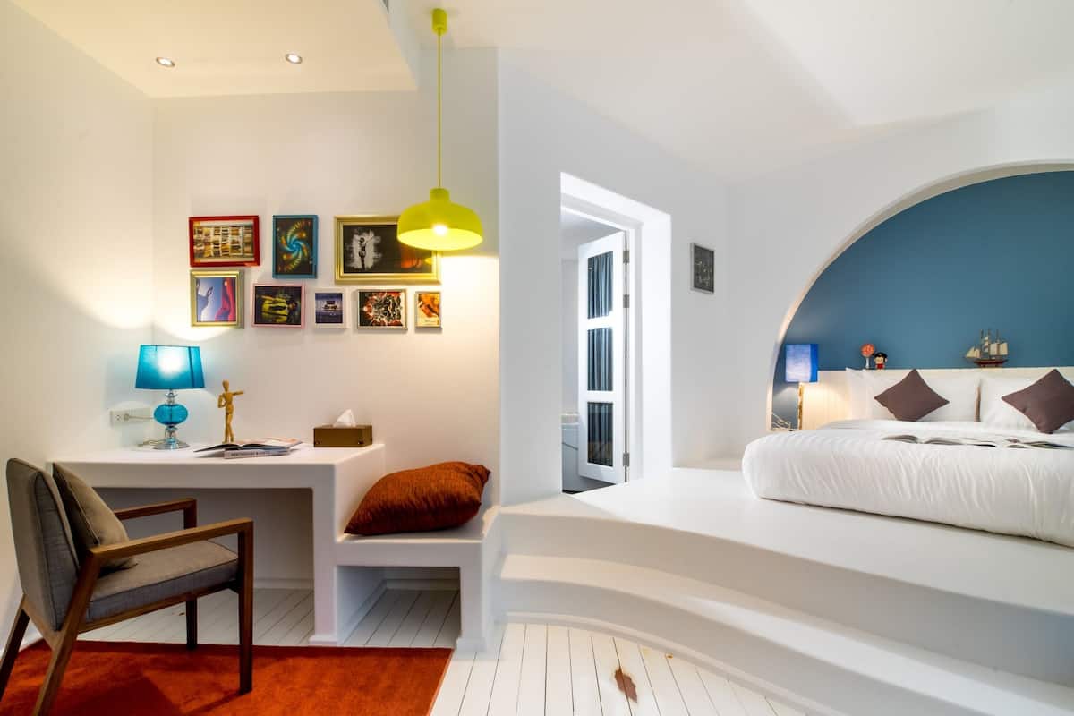A modern bedroom with a curved bed, a desk, and a chair.