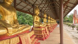 A row of golden Buddha statues under a covered walkway. - AP Grand Resort (Kanchanaburi)