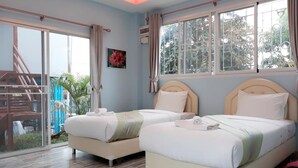 A hotel room with two beds, a large window with a view of greenery, and a balcony with a chair. - AP Grand Resort (Kanchanaburi)